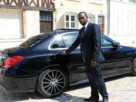 Homme en costume près d'une voiture noire élégante.